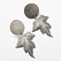 The Maple Allure Earrings By Skedio in silver, moonlight disk with sculpted maple leaf