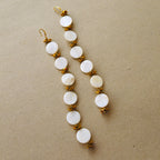 A pair of long dangling earrings with mother of pearl shells beads and gold toned cut glass beads