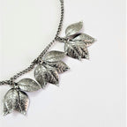 sculpted carved leaves handcrafted in brass are bunched together to create a garland like necklace