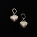 close up front shot of silver textured heart shape dangle drop earrings