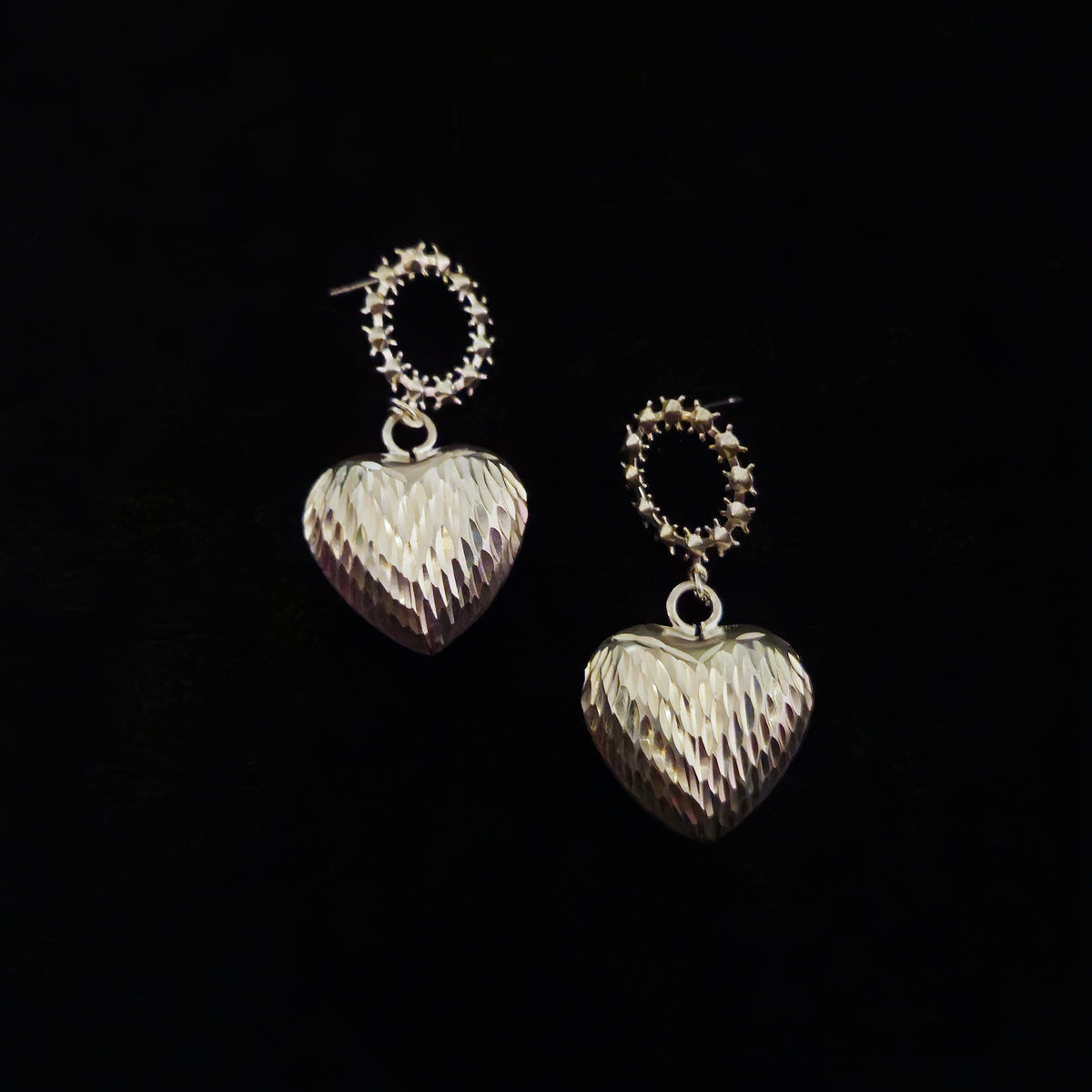 close up front shot of silver textured heart shape dangle drop earrings